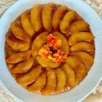 Upside-down peach tart garnished with edible flowers.