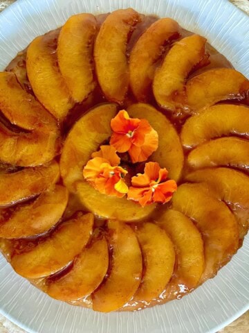 Upside-down peach tart garnished with edible flowers.
