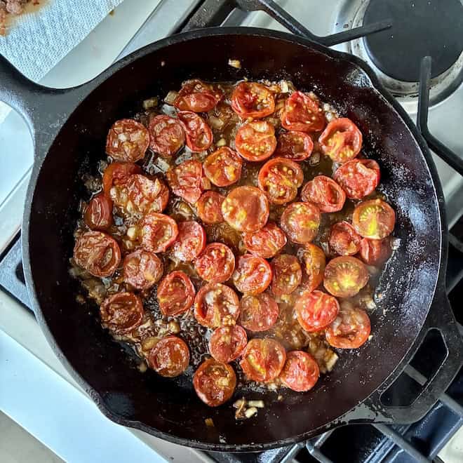 Caramelizing tomatoes and onions in a skillet.
