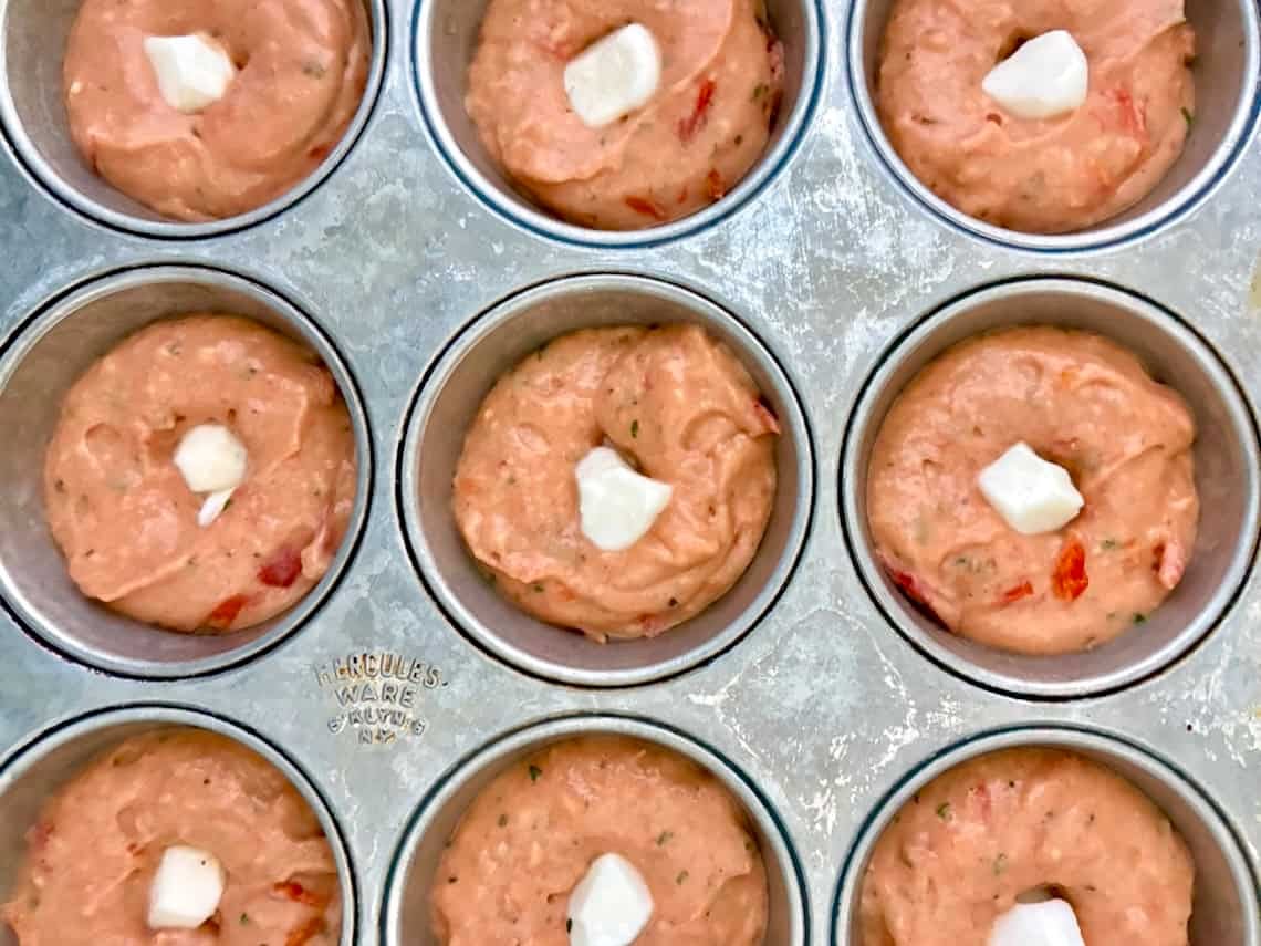 Pizza muffins with a mozzarella pearl in a muffin tin.